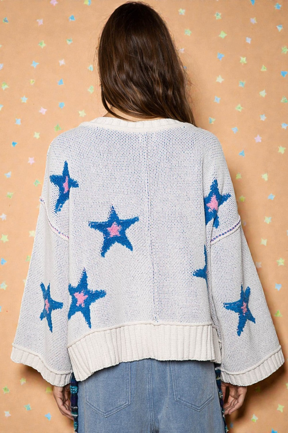 Person wearing a light blue sweater with star patterns on a patterned background