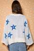 Person wearing a light blue sweater with star patterns on a patterned background