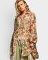 Woman wearing a floral patterned shirt over a green outfit on a white background