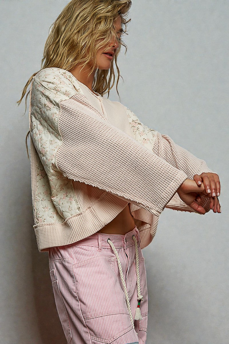 Woman wearing a light pink textured jacket and pink pants against a gray background