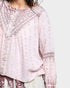 Light pink blouse with intricate patterns on a white background