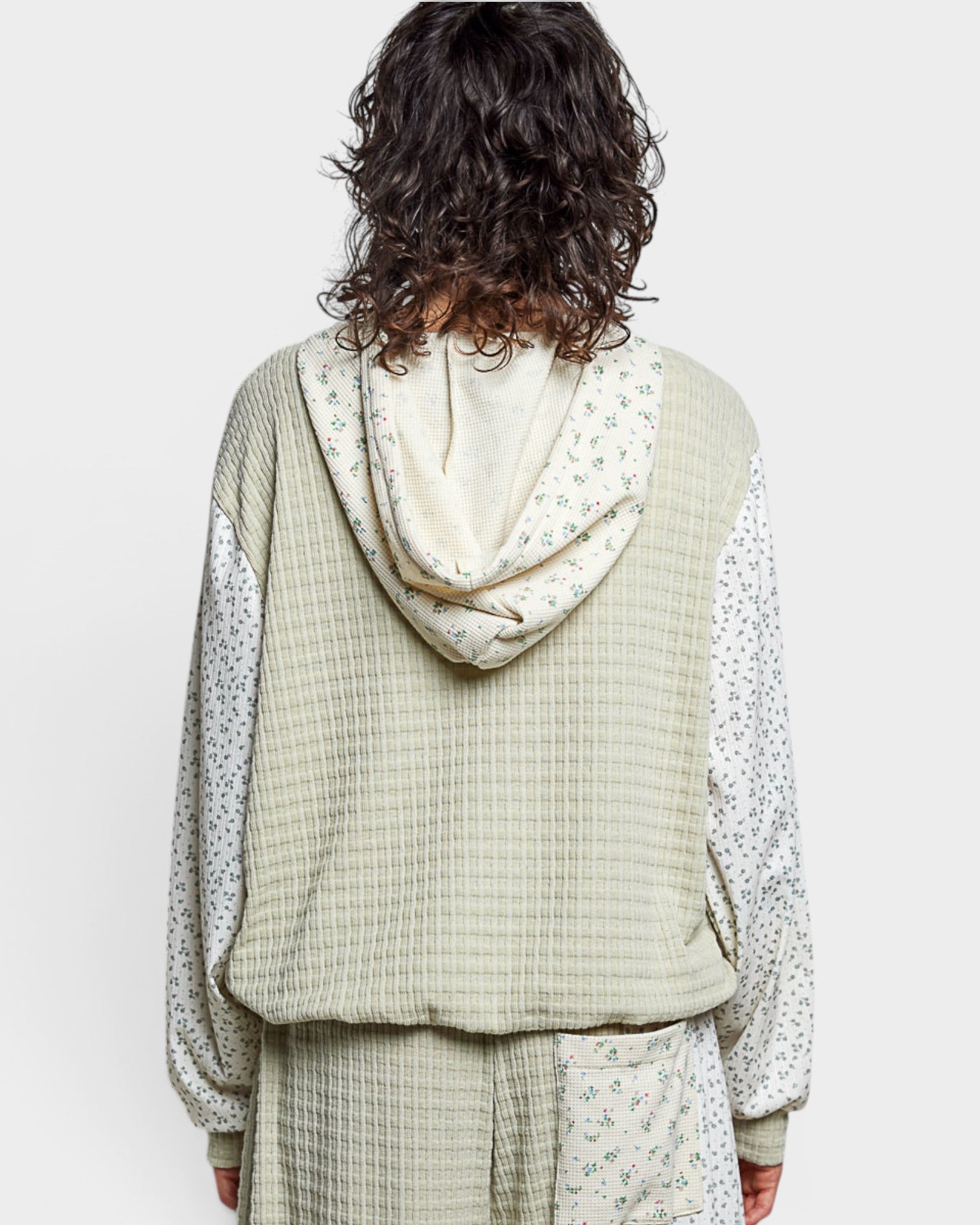 Person wearing a light green checkered outfit with a hood on a white background