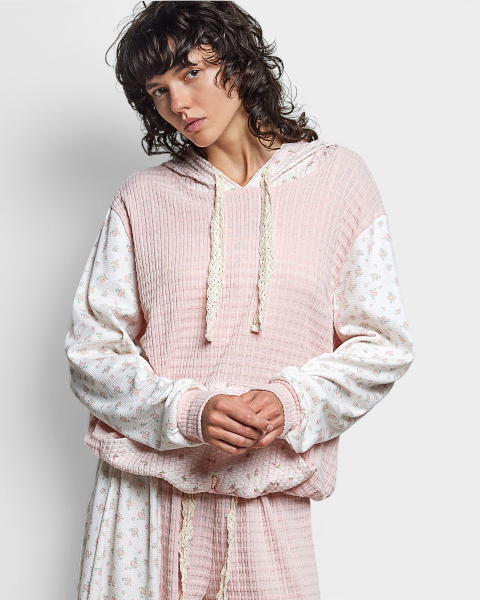 Person wearing a pink and white textured hoodie with a plain background