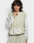 Woman wearing a green textured top with floral sleeves on a white background