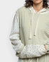 Person wearing a light green textured sweater over a floral shirt on a white background