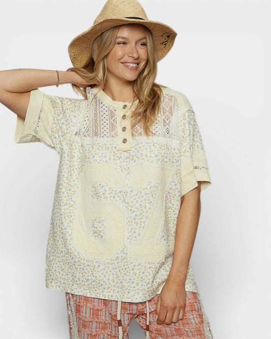 Woman wearing a floral blouse with a large number 67 on a plain background