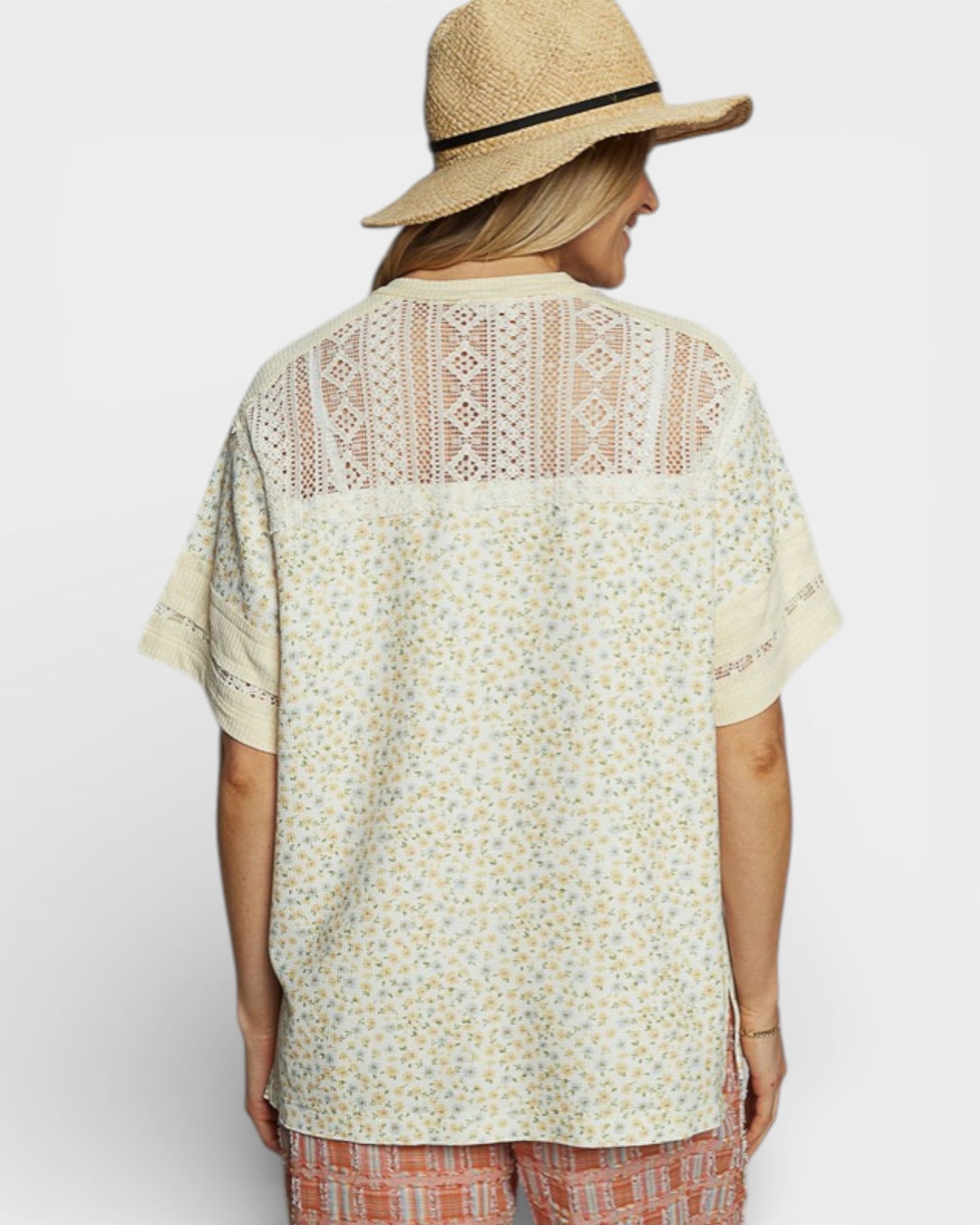 Person wearing a patterned shirt and straw hat on a plain background