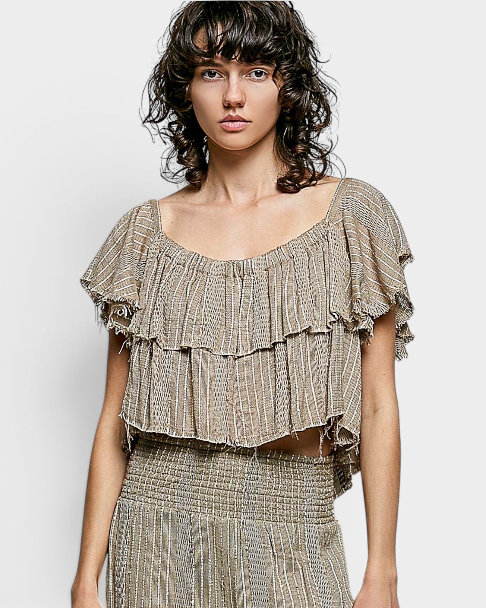 Woman wearing a ruffled top with a plain background