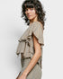 Woman wearing a textured, ruffled top against a plain background
