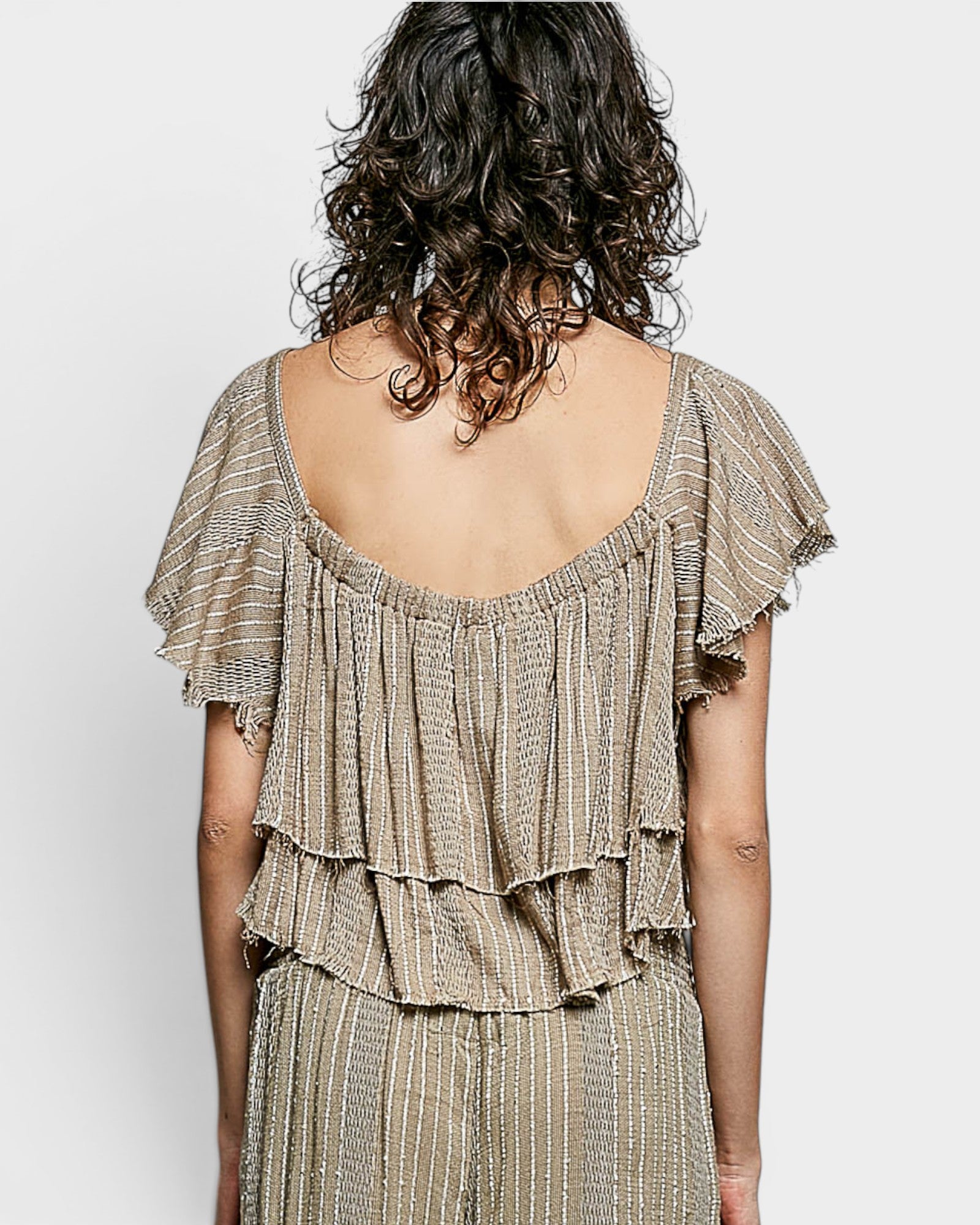 Woman wearing a beige ruffled dress with a plain background