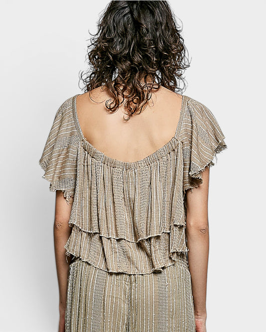 Woman wearing a beige ruffled dress with a plain background