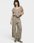 Woman wearing a patterned outfit with ruffled top and wide-leg pants on a white background