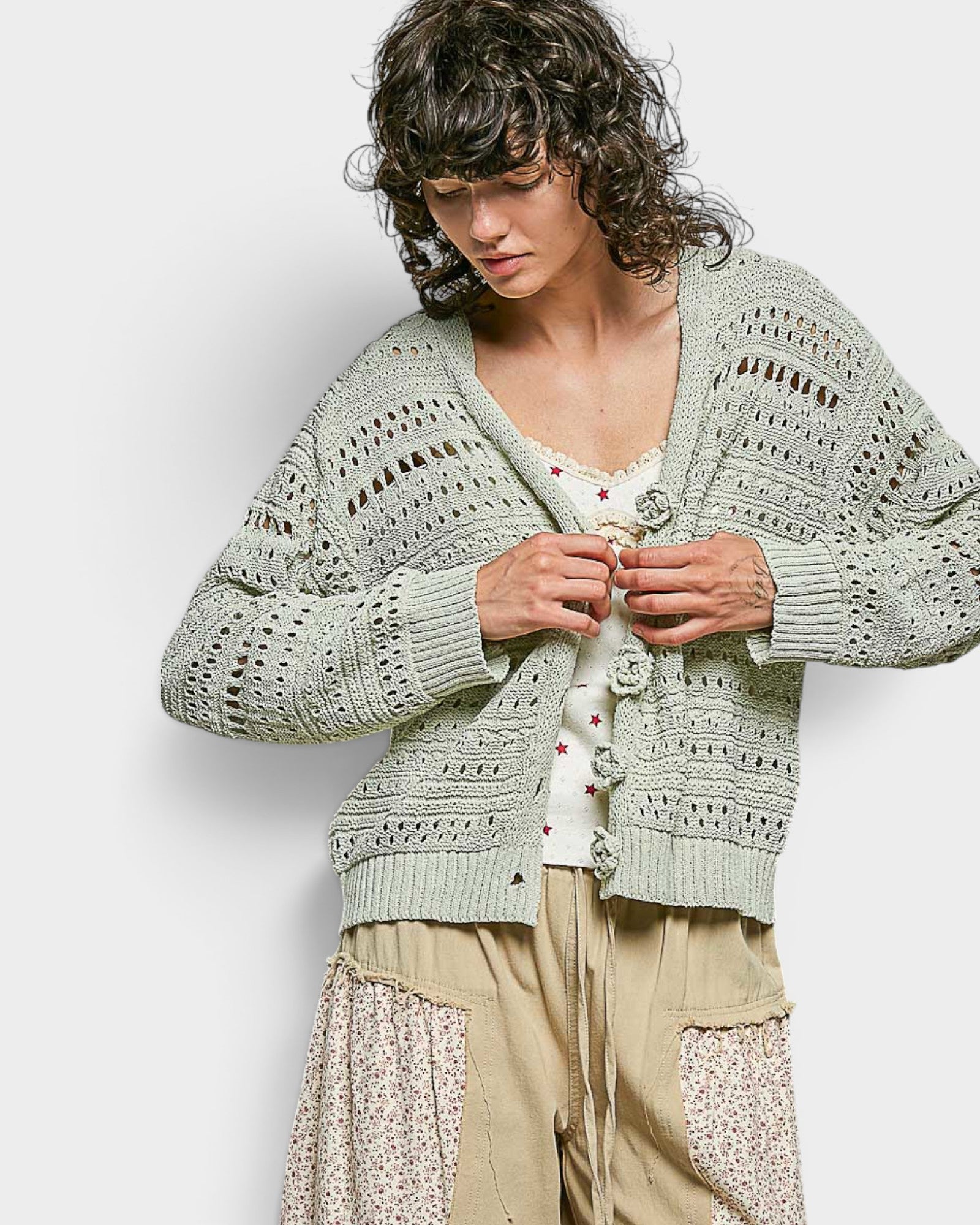 Woman wearing a light green knitted cardigan against a white background