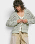 Woman wearing a light green knitted cardigan against a white background
