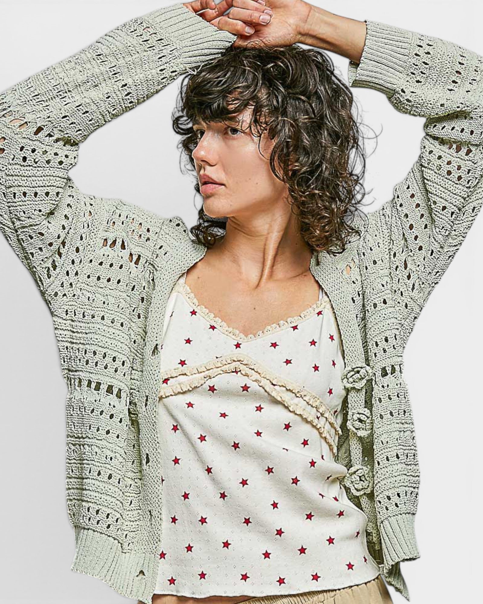 Woman wearing a patterned cardigan with a white top featuring red stars against a plain background