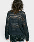 Person wearing a dark green crochet cardigan and shorts on a white background
