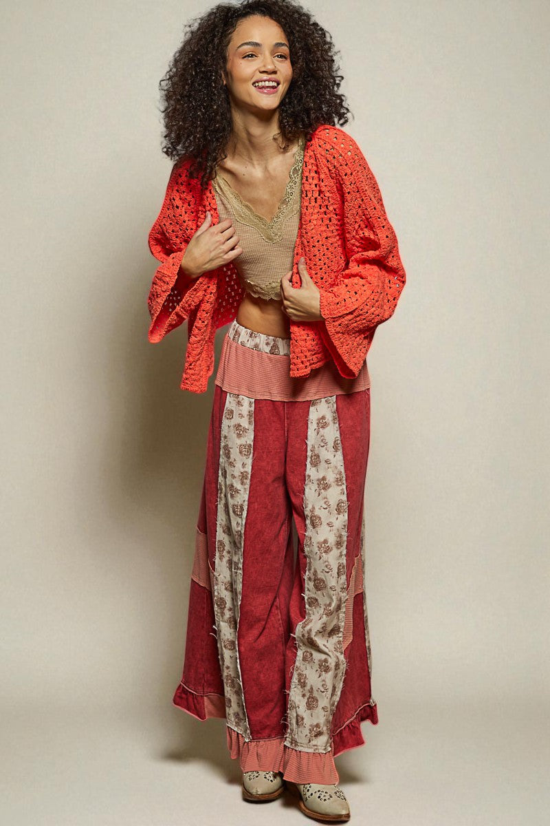 Woman wearing a red outfit with a beige top and floral pants against a plain background