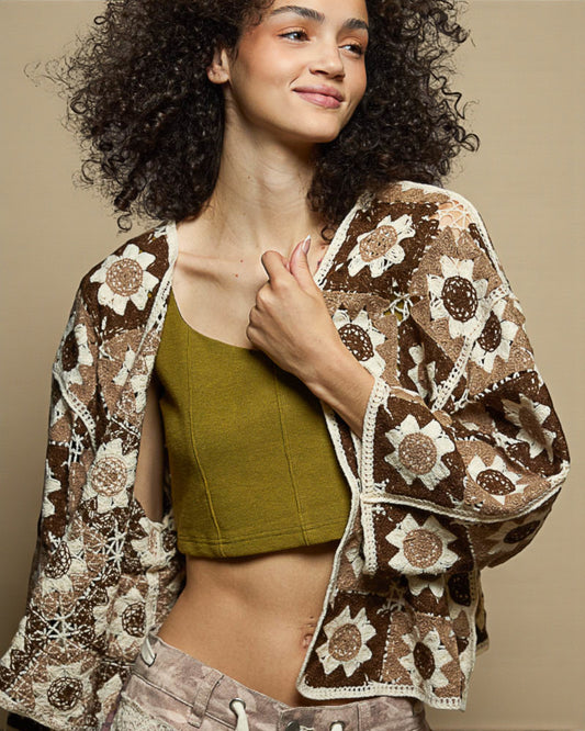 Woman wearing a brown floral-patterned cardigan over a green top against a beige background