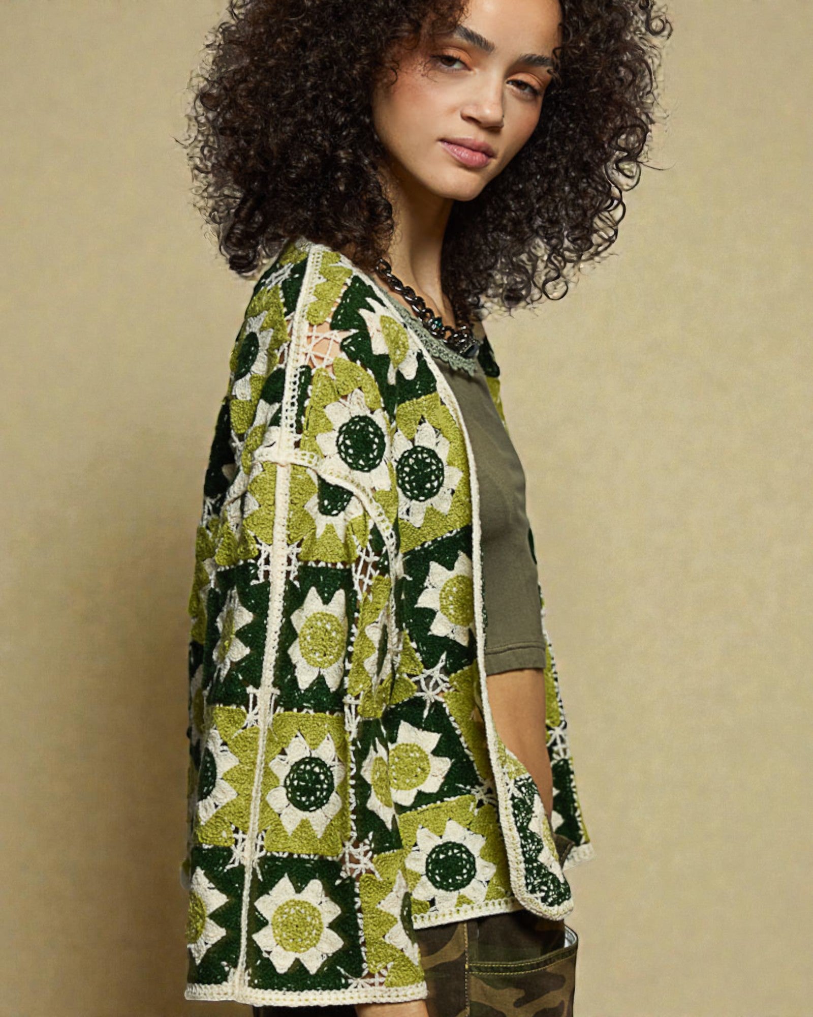 Woman wearing a green and white patterned cardigan against a beige background