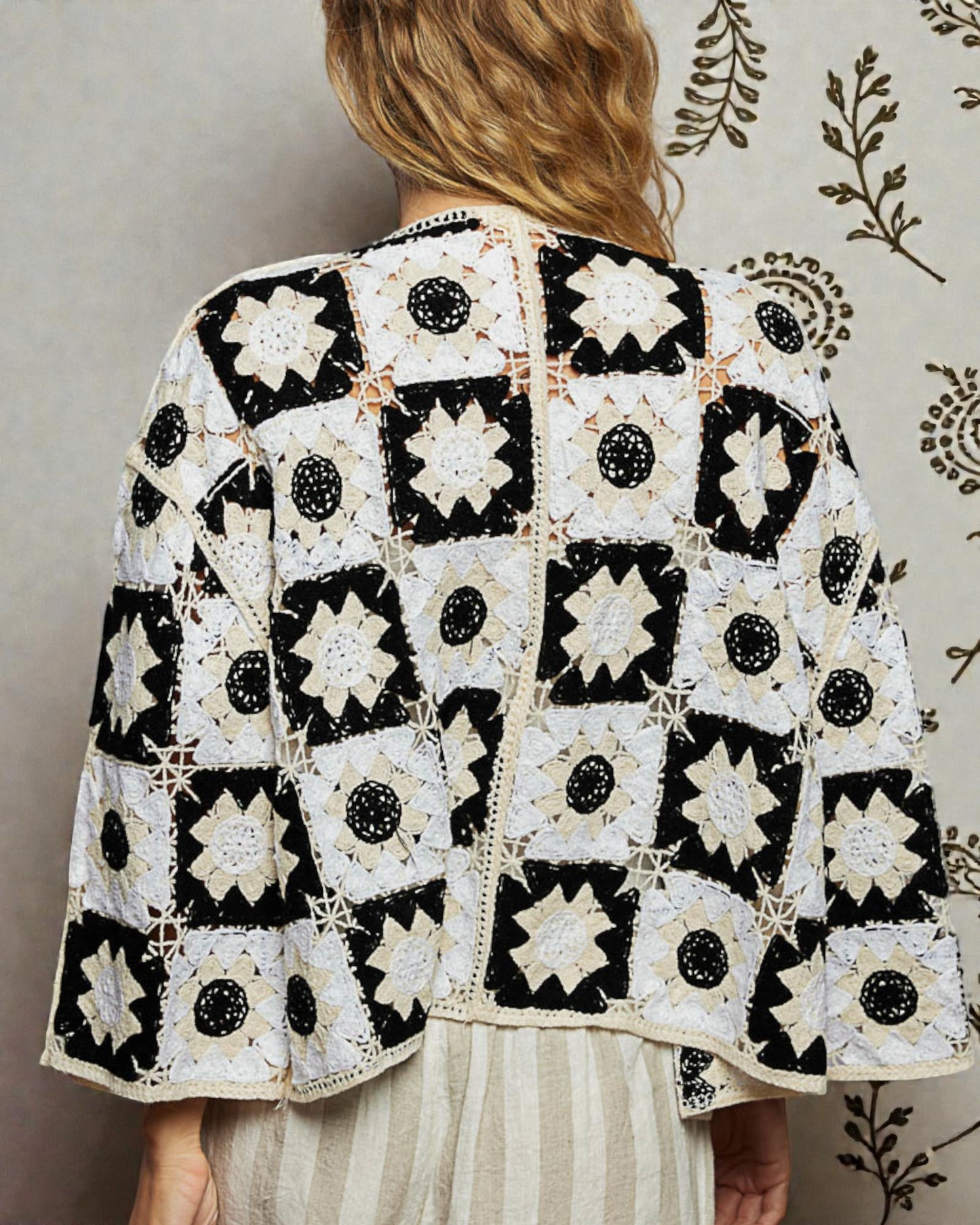 Person wearing a black and white patterned jacket against a neutral background