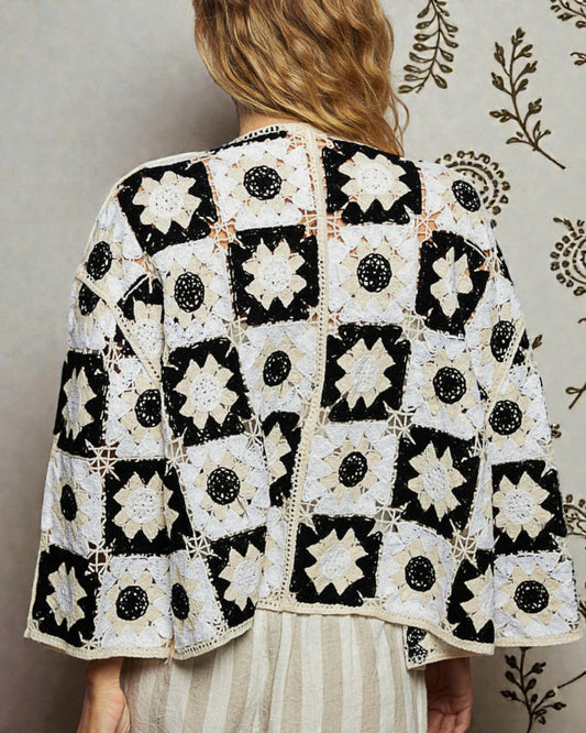 Person wearing a black and white patterned jacket against a neutral background