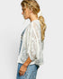 Woman wearing a white lace top and denim overalls on a plain background
