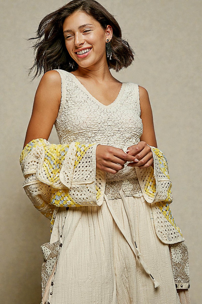 Woman wearing a cream-colored outfit with intricate patterns on a beige background