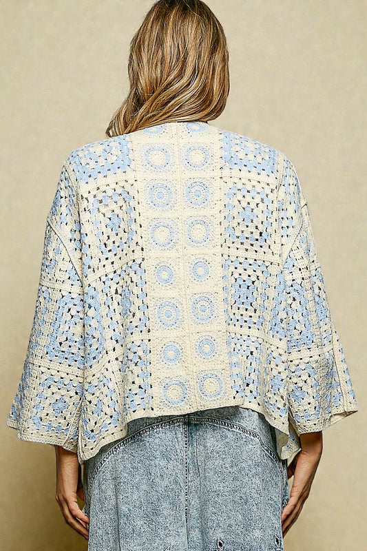 Person wearing a patterned kimono-style jacket against a beige background