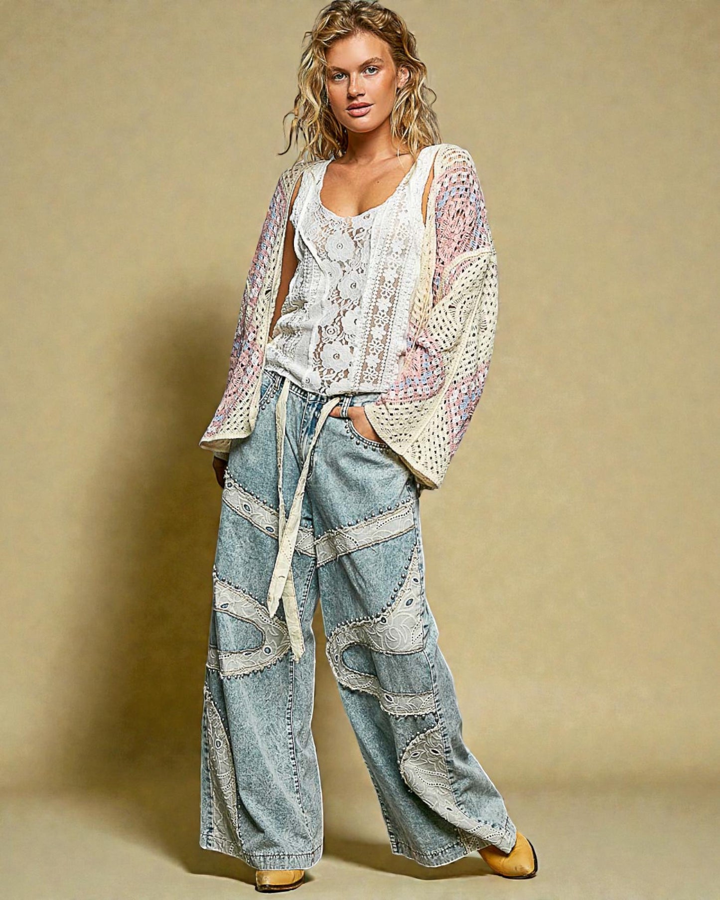 Woman wearing a patterned top and denim pants against a beige background