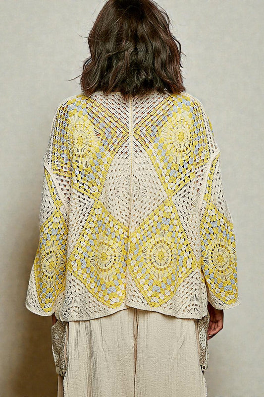 Person wearing a yellow and white patterned crochet top against a neutral background