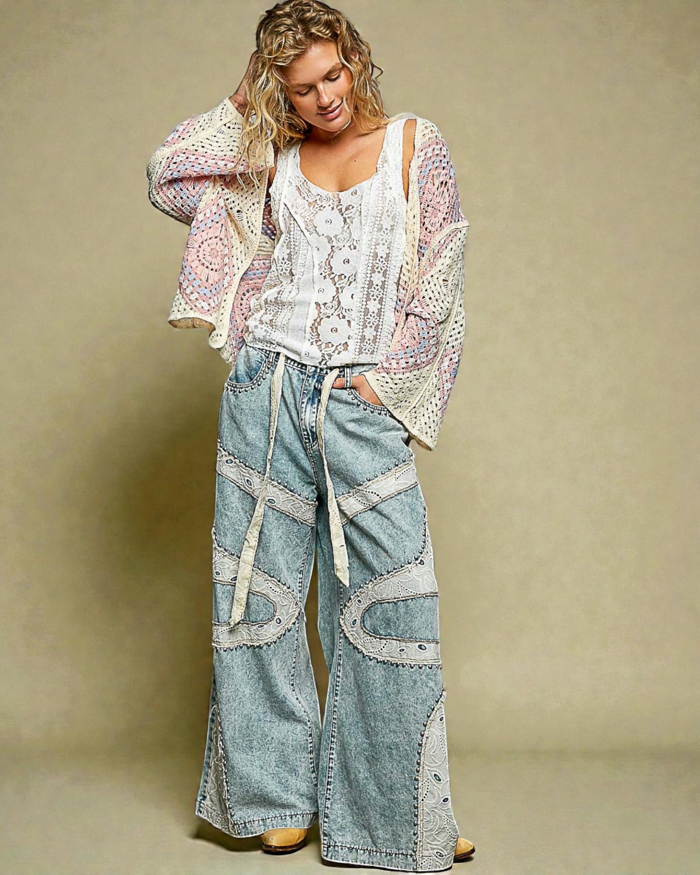 Woman wearing a patterned top and light blue jeans against a beige background