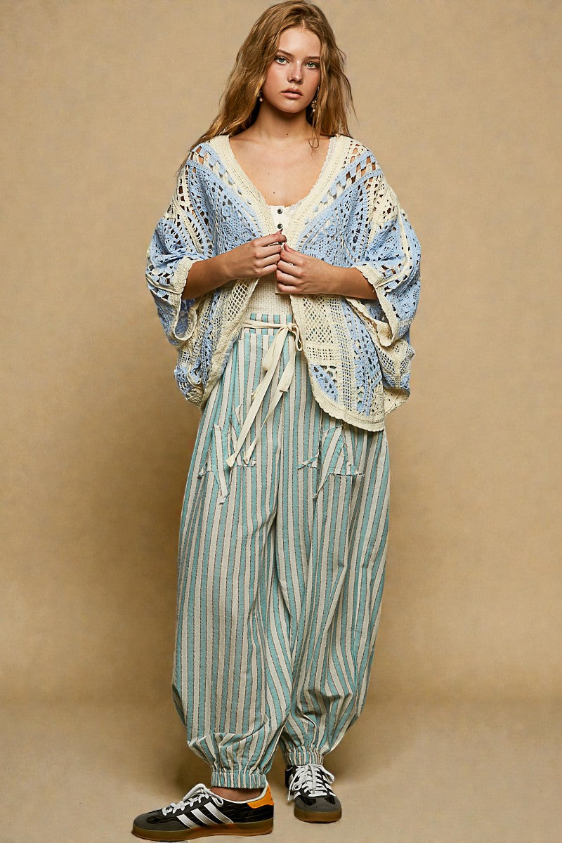 Woman wearing a blue and white patterned top and green striped pants against a beige background