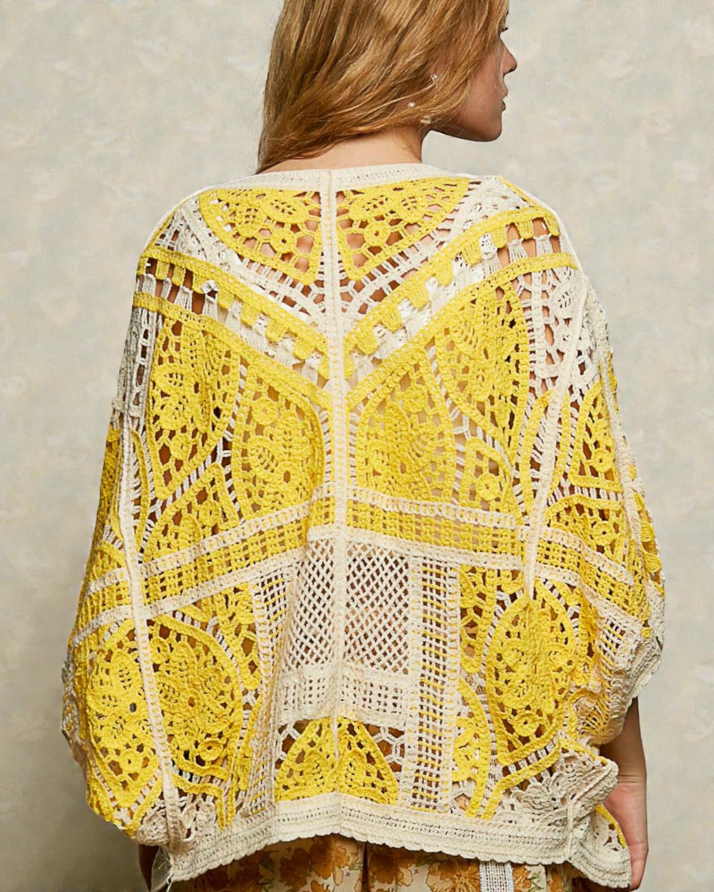 Woman wearing a yellow and white crochet top against a neutral background