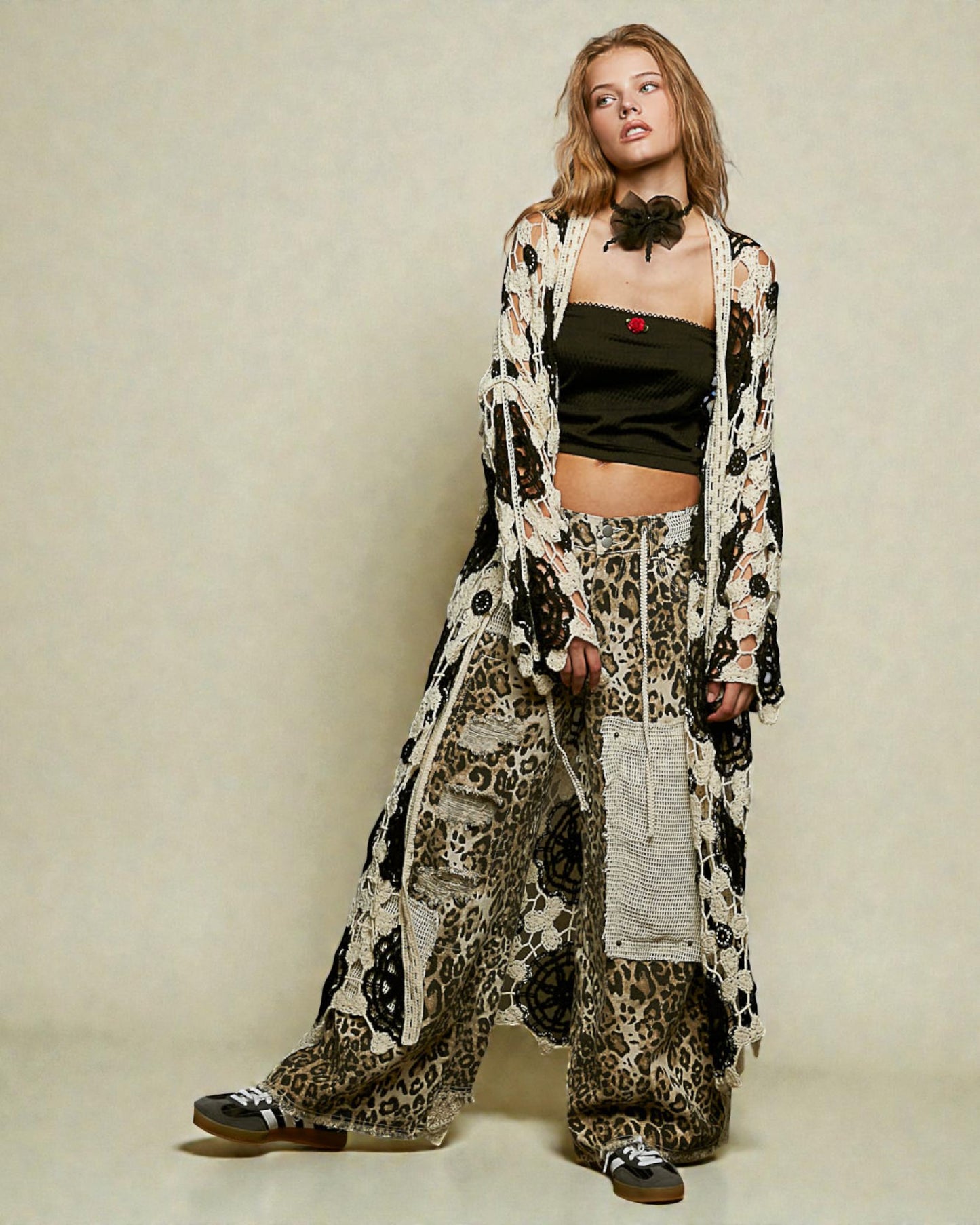 Woman wearing a long, patterned coat over a leopard print outfit on a plain background