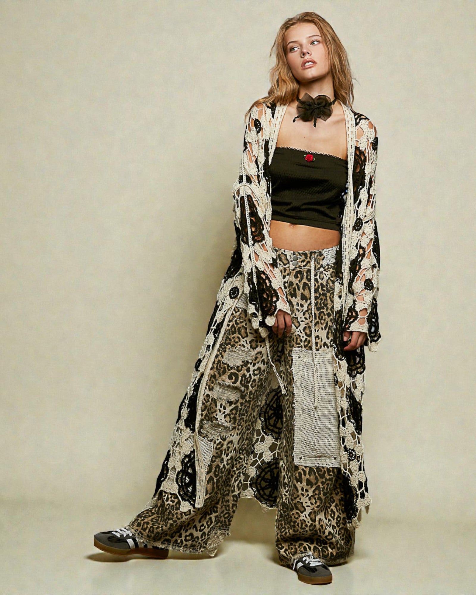 Woman wearing a long, patterned coat over a leopard print outfit on a plain background