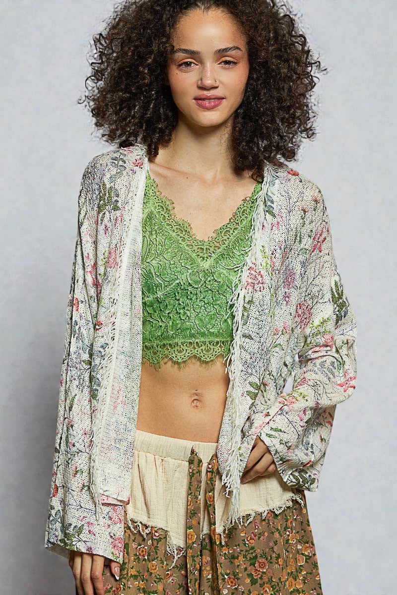 Woman wearing a floral kimono over a green lace top on a gray background