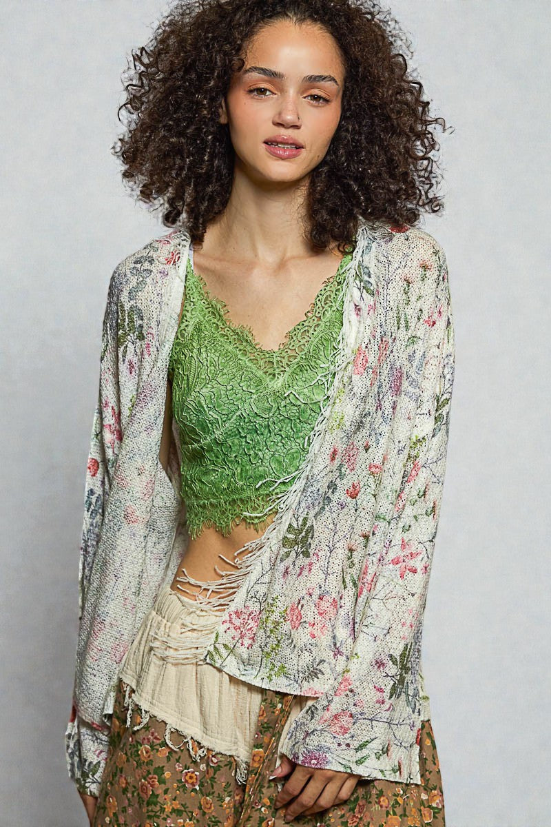 Woman wearing a green lace top and floral kimono against a gray background