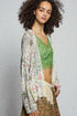 Woman wearing a floral kimono over a green top against a plain background