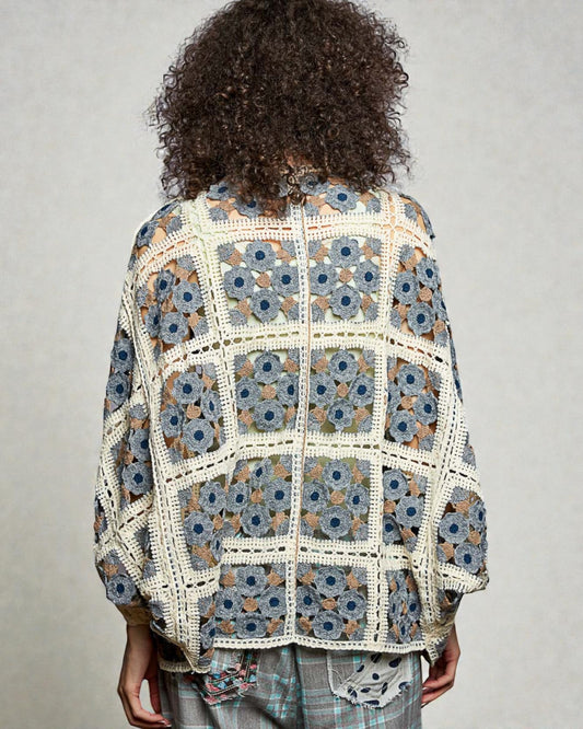 Person wearing a floral crochet jacket on a plain background