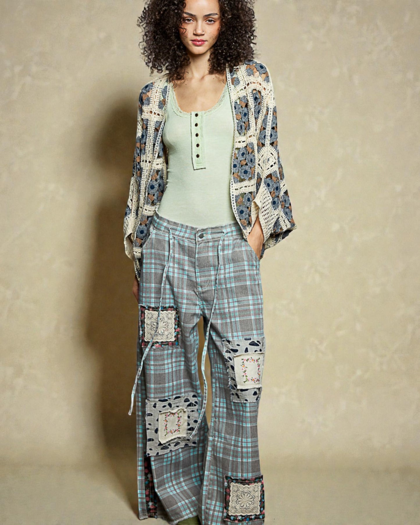Woman wearing a patterned outfit with plaid pants and a matching jacket against a beige background