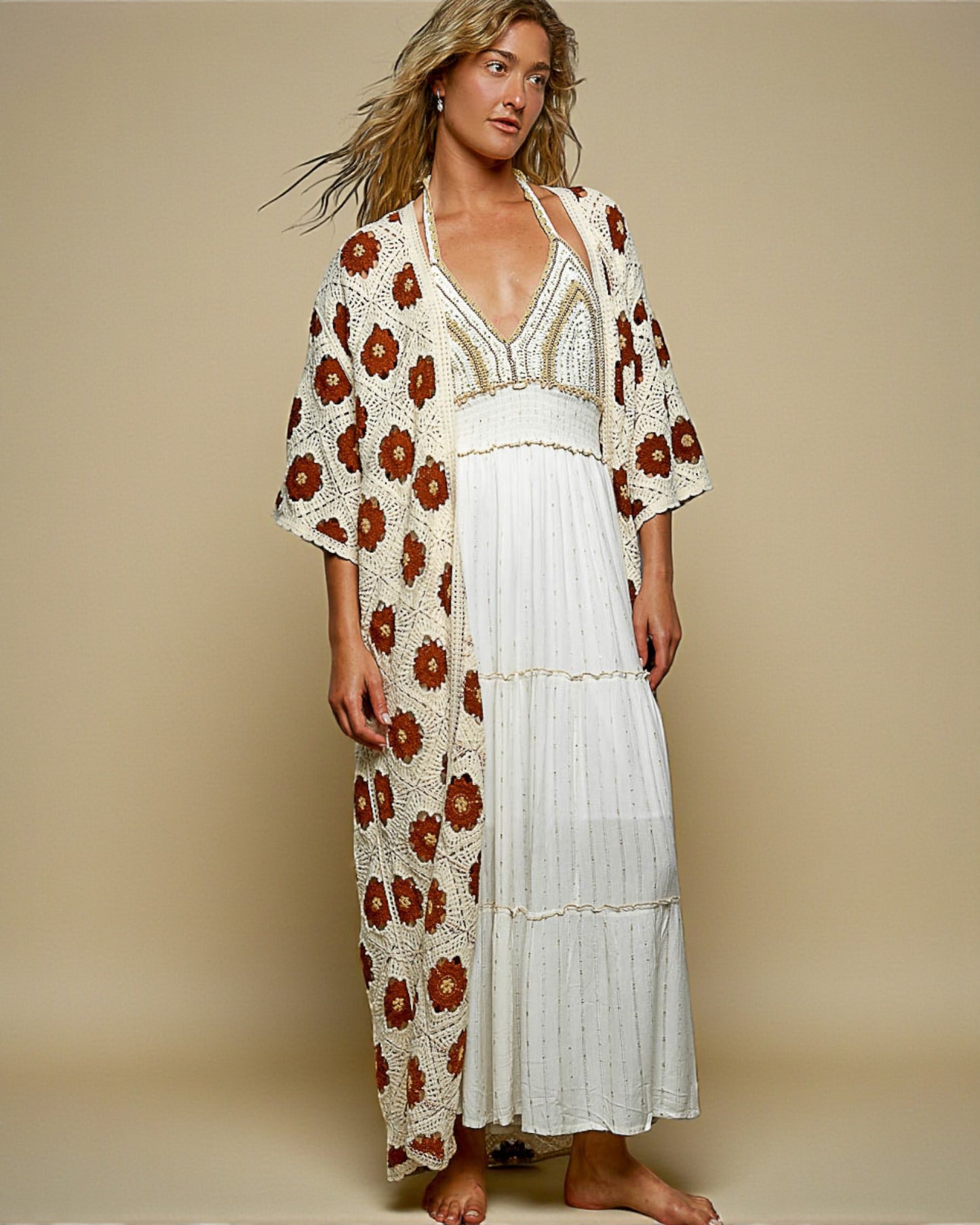 Woman wearing a white dress with a floral kimono over it on a beige background