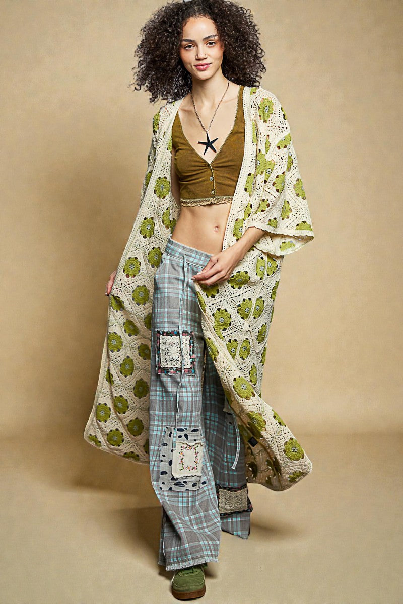 Woman wearing a long, patterned kimono-style garment over a casual outfit on a beige background