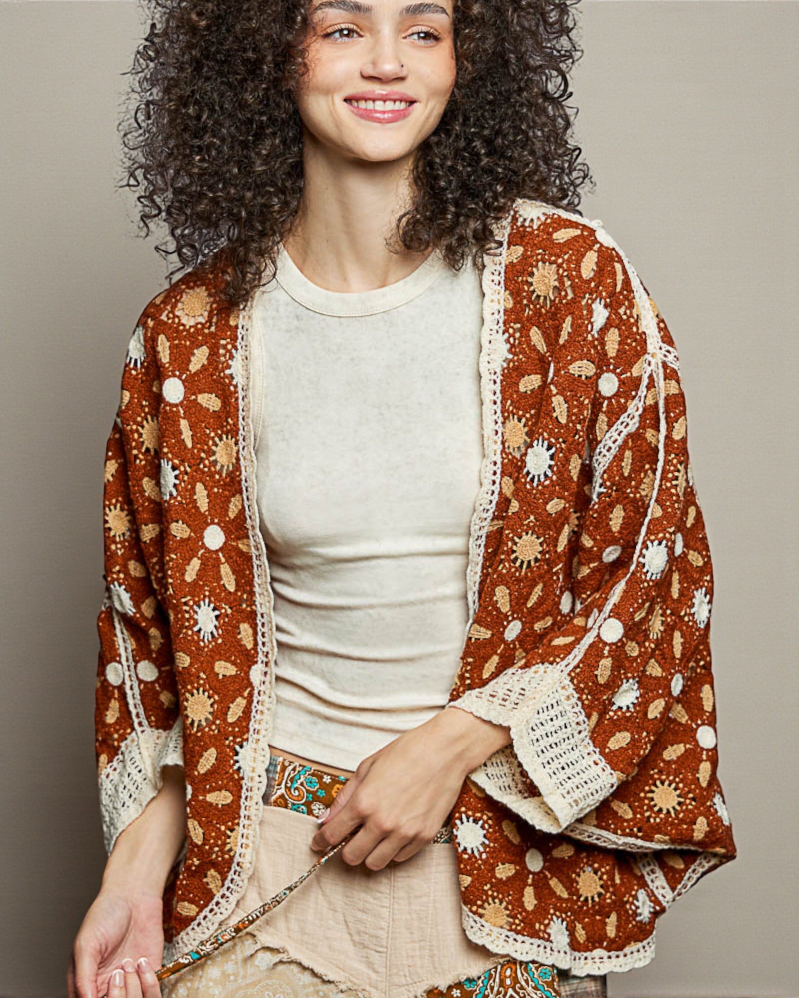 Woman wearing a patterned brown jacket over a white shirt on a plain background