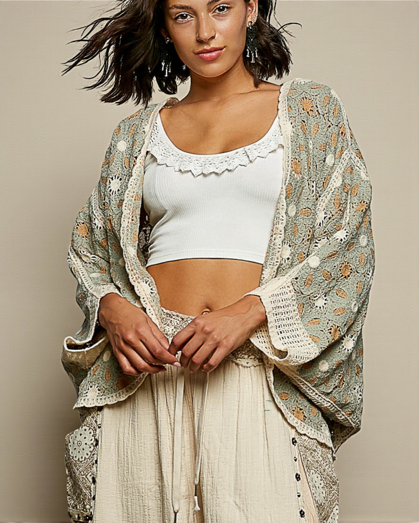 Woman wearing a white top and beige skirt with a patterned shawl against a neutral background