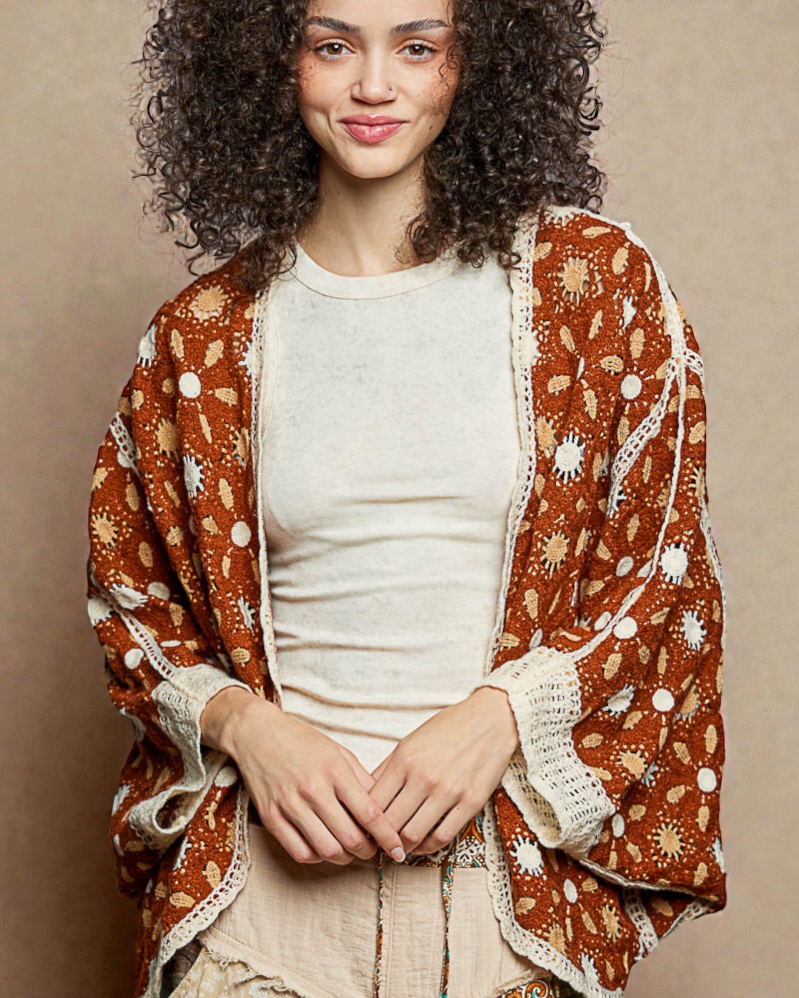 Woman wearing a patterned brown cardigan over a white shirt on a beige background