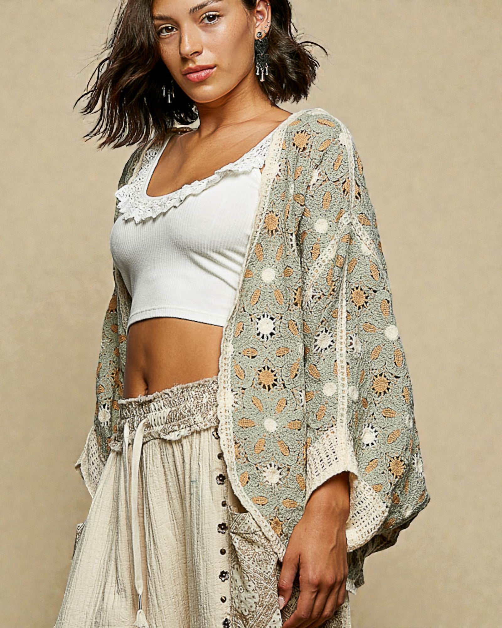 Woman wearing a white top and patterned kimono against a beige background