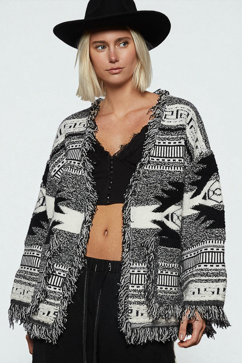 Woman wearing a patterned cardigan over a black top on a white background
