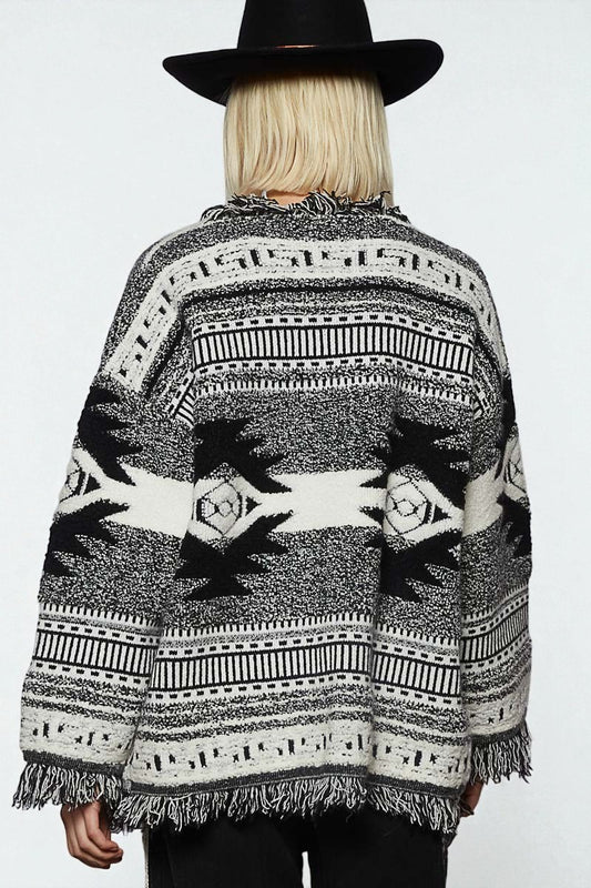 Person wearing a patterned poncho with a plain background