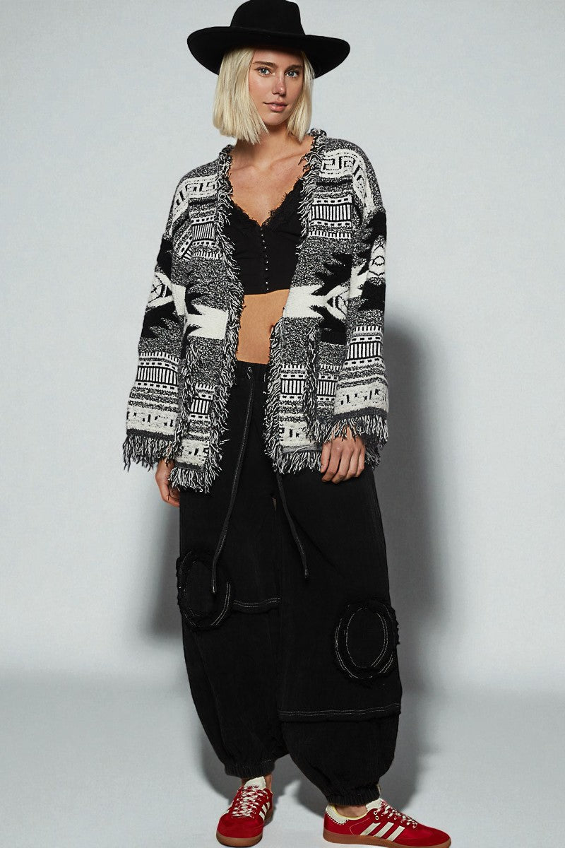 Person wearing a patterned cardigan, black pants, and red shoes on a white background