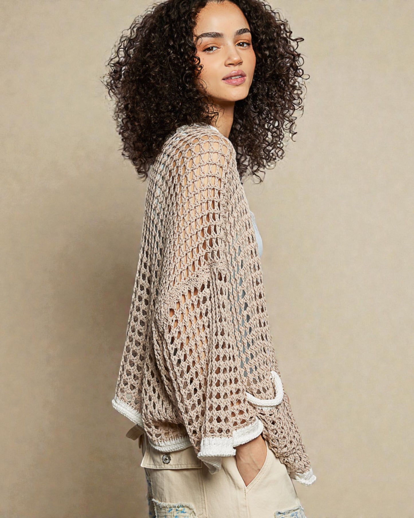 Woman wearing a beige crochet cardigan against a beige background